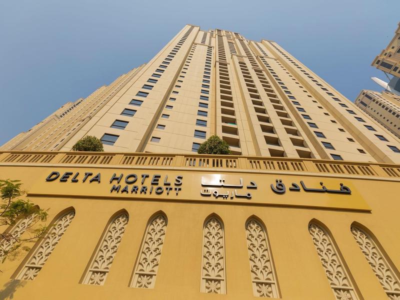 Widok w górę na wysoki budynek Delta Hotels Marriott pod niebieskim niebem.