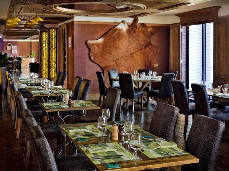 Elegancka restauracja z nakrytymi stołami i ciemnymi krzesłami w ciepłej atmosferze.