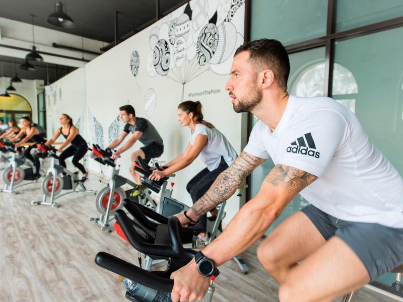Mehrere Personen trainieren auf stationären Fahrrädern in einem hellen Fitnessraum.