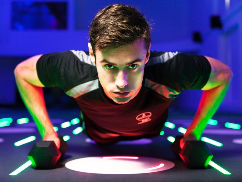 Junger Mann macht Liegestütze auf einer beleuchteten Fitnessmatte.