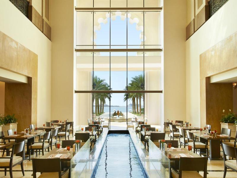 Elegantes Hotelrestaurant mit Wasserspiegel und weitem Blick auf Palmen und Meer.