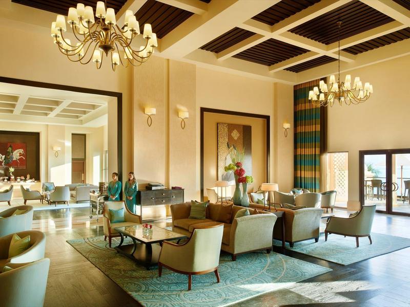 Eleganter Sitzbereich in einem Hotel mit Kronleuchtern und großen Spiegeln.