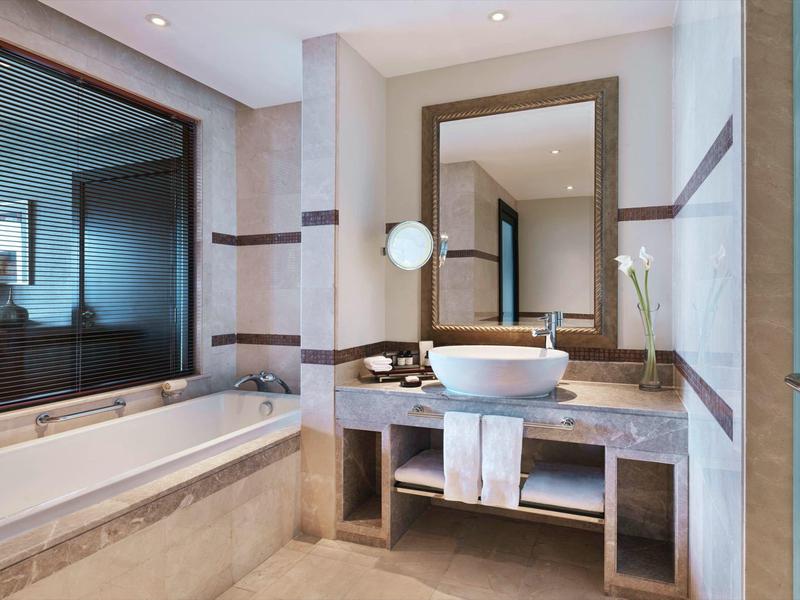 Elegantes Badezimmer mit Badewanne, großem Spiegel und modernen Waschbecken in neutralem Design.