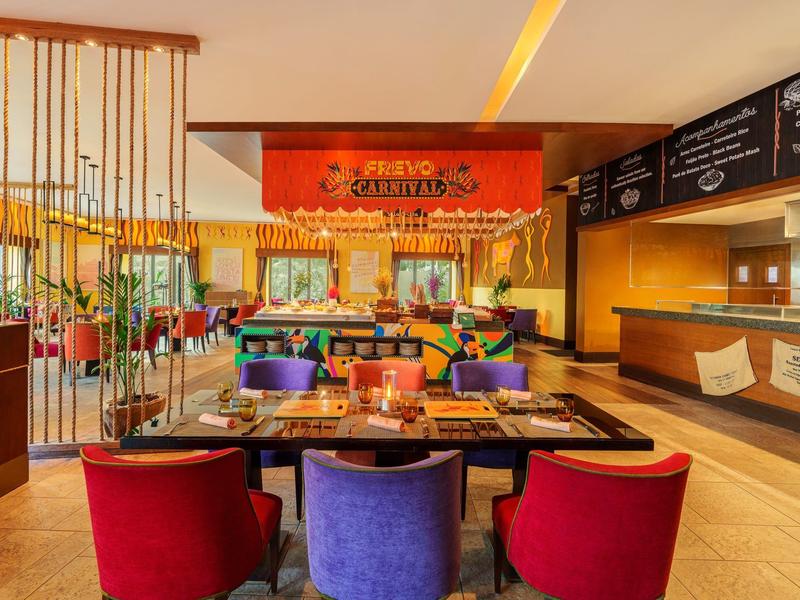 Farbenfrohes Restaurant mit roten und violetten Stühlen sowie dekoriertem Buffetbereich.