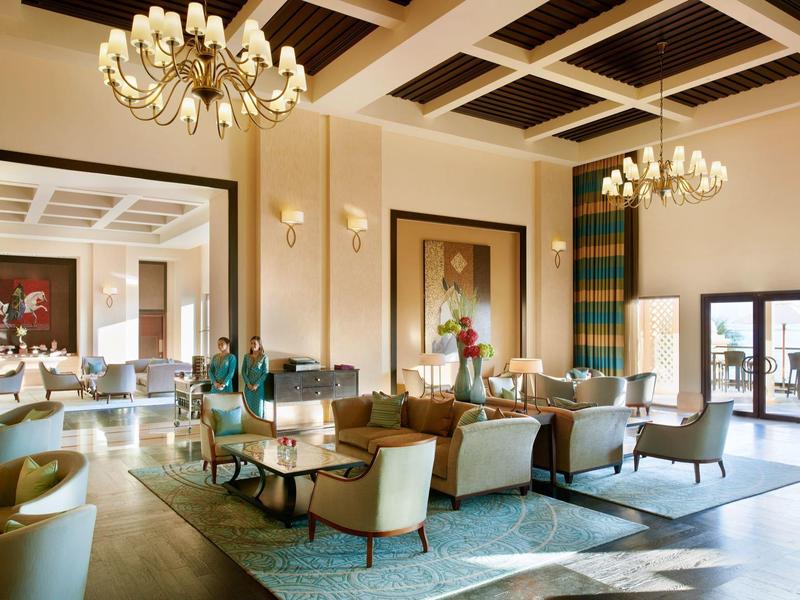 Eleganter Hotel-Loungebereich mit bequemen Sesseln, Kronleuchtern und großen Fenstern.