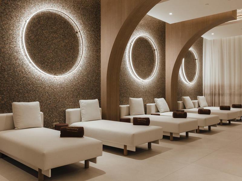 Moderne Ruhelounge mit weißen Liegen und rundem Wandlicht im eleganten Ambiente.