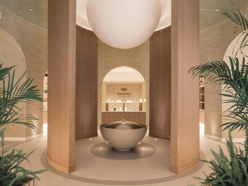 Eleganter Wellnessbereich mit zentralem Wasserbecken, warmen Holzakzenten und grünen Pflanzen.