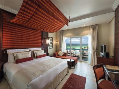 Modernes Hotelzimmer mit Doppelbett, Balkon und Meerblick bei Tageslicht.