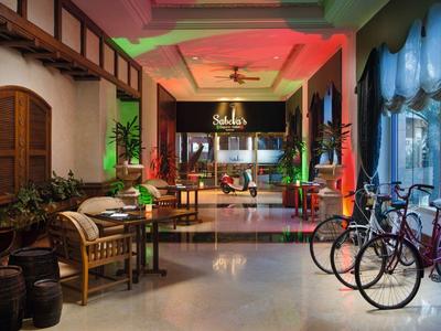 Heller Hotel-Eingangsbereich mit Sitzgelegenheiten, Fahrrädern und Pflanzen in modernem Design.