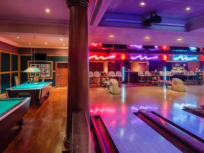 Innenansicht von Unterhaltungsräumen mit Billardtischen und einer Bowlingbahn in einem Hotel.