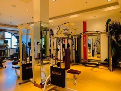 Innenansicht eines Fitnessraums im Hotel mit verschiedenen Trainingsgeräten und Spiegeln