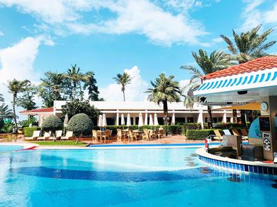 Pool mit Swim-up-Bar und Palmen in tropischem Hotelresort unter blauem Himmel