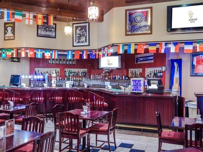 Innenraum einer Bar mit Holzmöbeln, Flaggen und Fernsehern an der Wand.