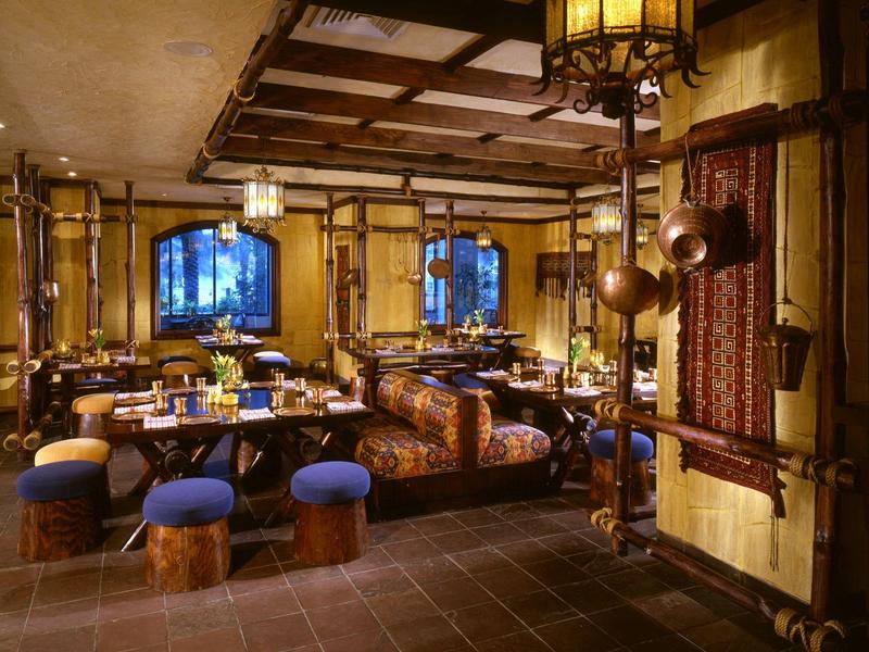 Gemütlicher Hotelrestaurantbereich mit rustikalem Holzdekor und blau gepolsterten Hockern.