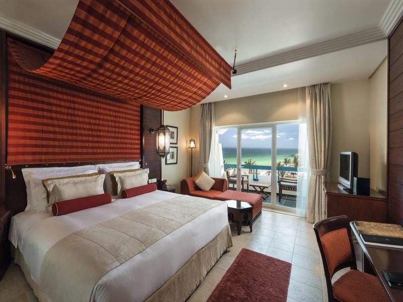 Modernes Hotelzimmer mit Doppelbett, Balkon und Meerblick bei Tageslicht.