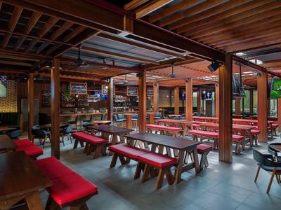 Großer Innenraum eines Restaurants mit Holztischen und roten Sitzpolstern in einem Hotel.