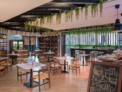 Modernes Hotelrestaurant mit Holzmöbeln, Pflanzen und gemütlicher Atmosphäre.