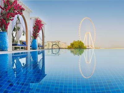 Infinity-Pool mit blauem Wasser und Blick auf ein Riesenrad bei klarem Himmel