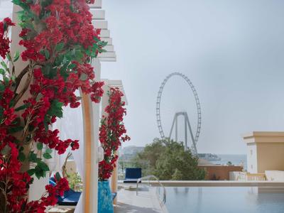 Rote Blumen an einem weißen Gebäude mit Blick auf ein Riesenrad an einem bewölkten Tag