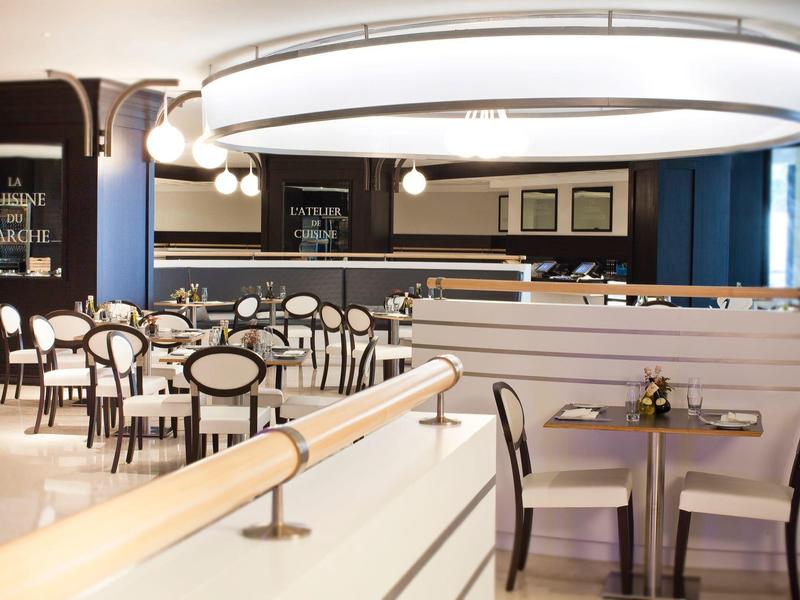 Restaurant élégant avec tables, chaises et éclairage moderne.