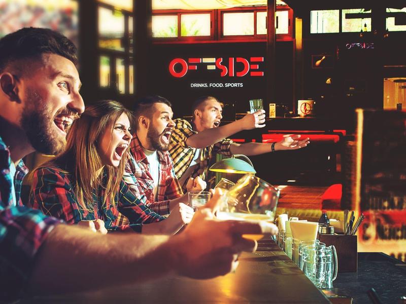 Des amis profitent de boissons et de divertissements dans un bar d'hôtel animé.