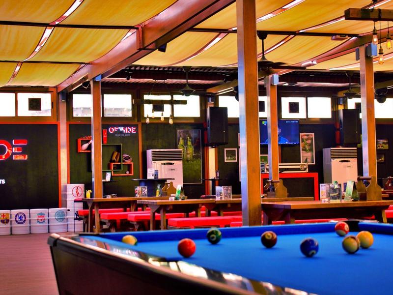 Table de billard dans un bar chaleureux avec chaises rouges et auvent jaune
