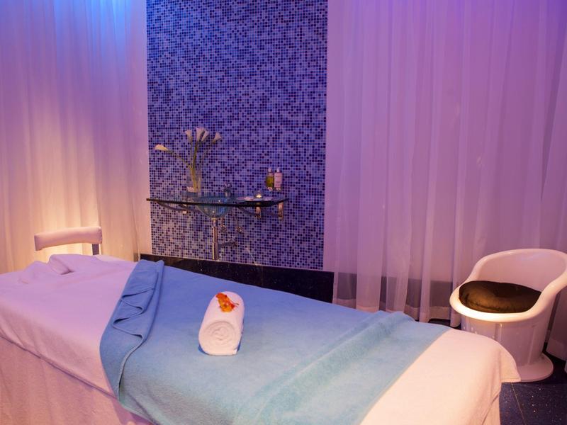 Salle de bien-être calme avec table de massage, serviette bleue et éclairage tamisé.