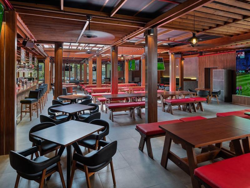 Bar d'hôtel moderne avec tables, chaises et bancs en bois chaleureux.