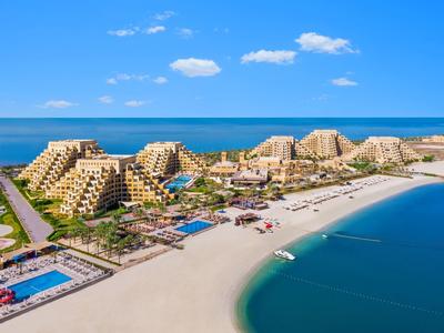 Strand mit klarem Wasser, großer Sandfläche, mehreren Pyramiden-förmigen Hotels und blauen Pools.