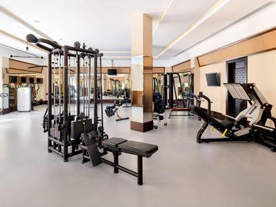 Heller, moderner Fitnessraum mit Kraftmaschinen, Spiegelwänden und weißen Wänden.