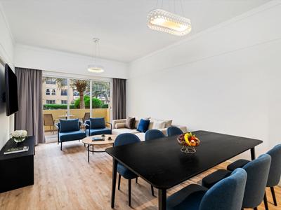 Moderner Ess- und Wohnbereich mit schwarzen Möbeln und blauem Sitzbereich, Balkon im Hintergrund.