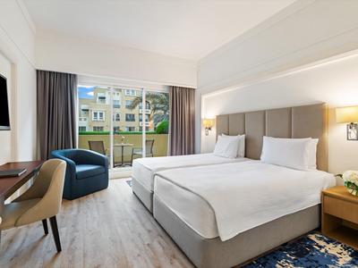 Modernes Hotelzimmer mit großem Bett, Balkonblick und moderner Einrichtung.