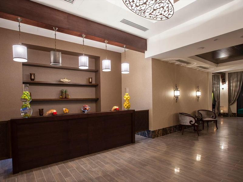 Moderner Hotellobby-Empfangsbereich mit dunkler Holztheke und bequemen Sitzgelegenheiten.