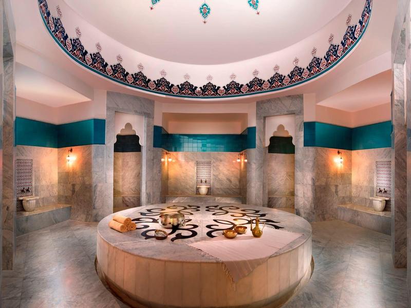 Kreisförmiger Raum mit einer Kuppel und dekorativen Mustern, zentraler Marmorplatte, warmes Licht