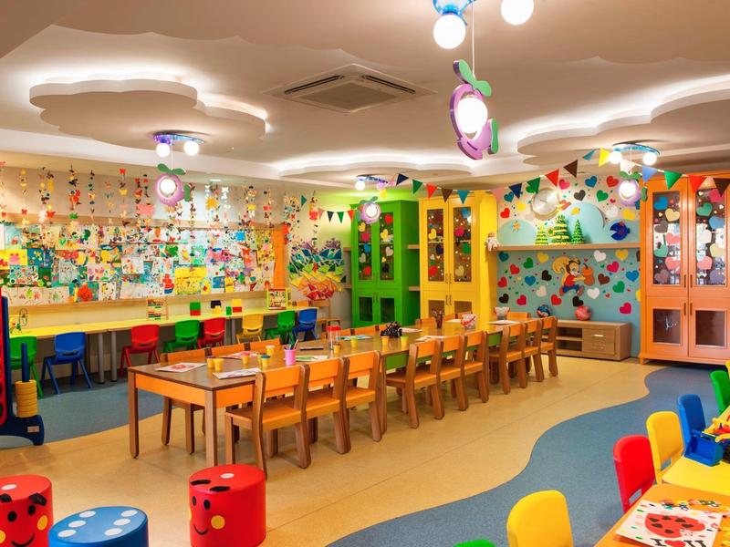 Bunter Kinderspielraum mit Tischen, Stühlen und Spielzeug in lebendiger Atmosphäre.