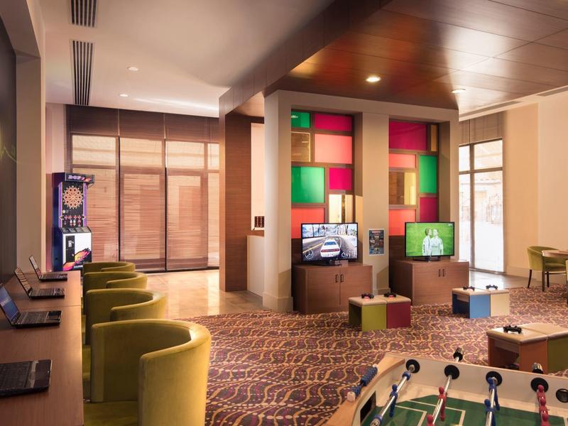 Modernes Hotelzimmer mit Spielbereich, bunten Wandakzenten und bequemen Sesseln.