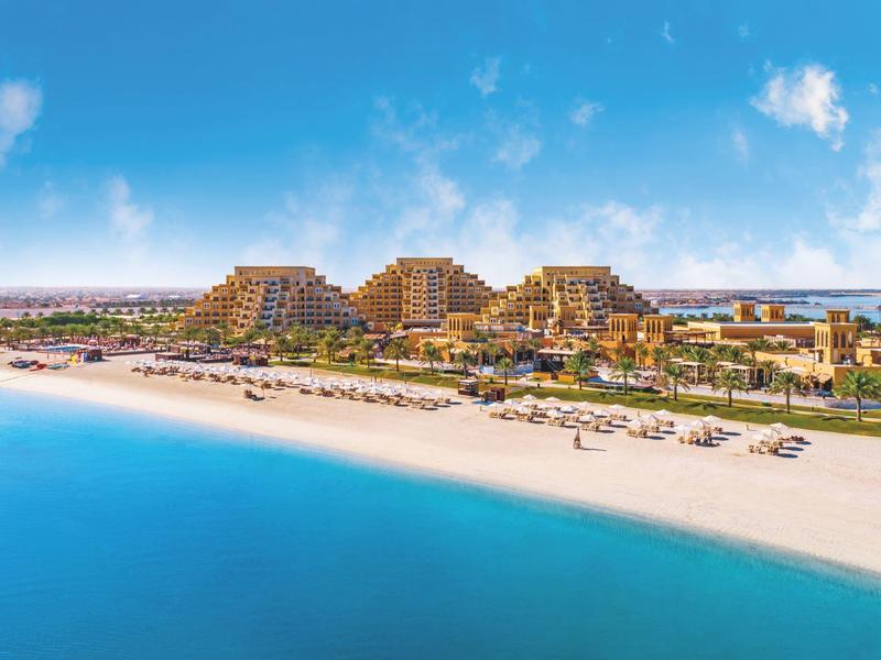 Pyramidenförmige Hotels an einem weißen Sandstrand mit blauem Meer unter blauem Himmel
