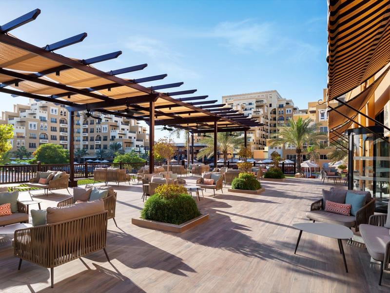 Große Außenterrasse mit Stühlen, Tischen und Sonnenschutz in einem Hotel.