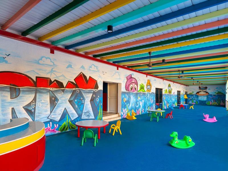 Bunter Indoor-Spielplatz mit Sitzgelegenheiten und großer RIXY-Wandgestaltung.