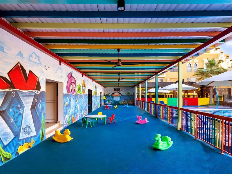 Bunte überdachte Kinderspielecke mit Sitzgelegenheiten und Graffiti an der Wand.