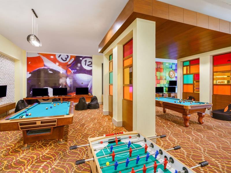 Freizeitraum mit Billardtischen, Tischfußball und bunter Wanddekoration in einem Hotel.