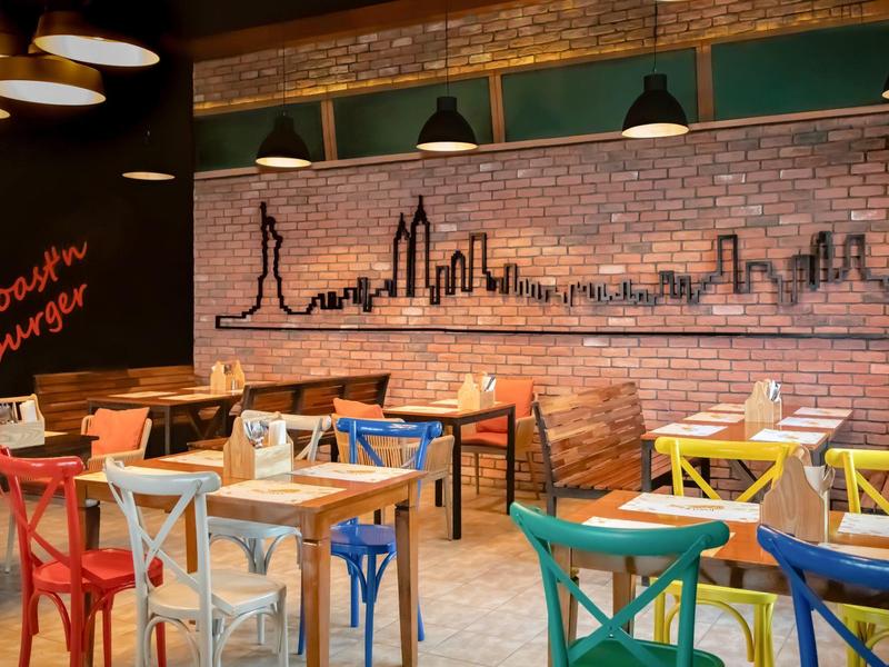 Modernes Burger-Restaurant mit bunten Stühlen und Backsteinwand mit Skyline-Graffiti.