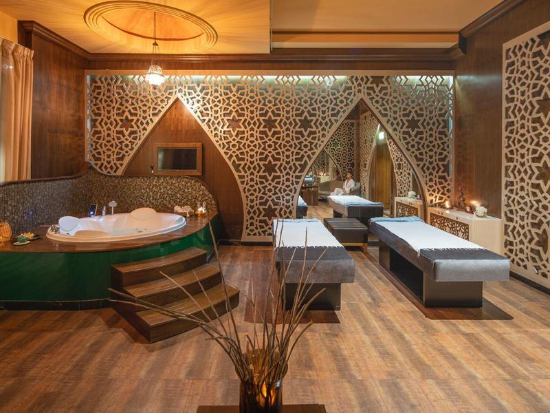 Luxuriöses Spa mit Whirlpool, Liegen und dekorativen Wandelementen in warmen Tönen.