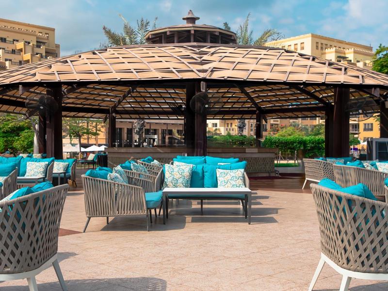 Gemütliche Außensitzbereiche mit blauen Kissen unter einem überdachten Pavillon in einem Hotel.