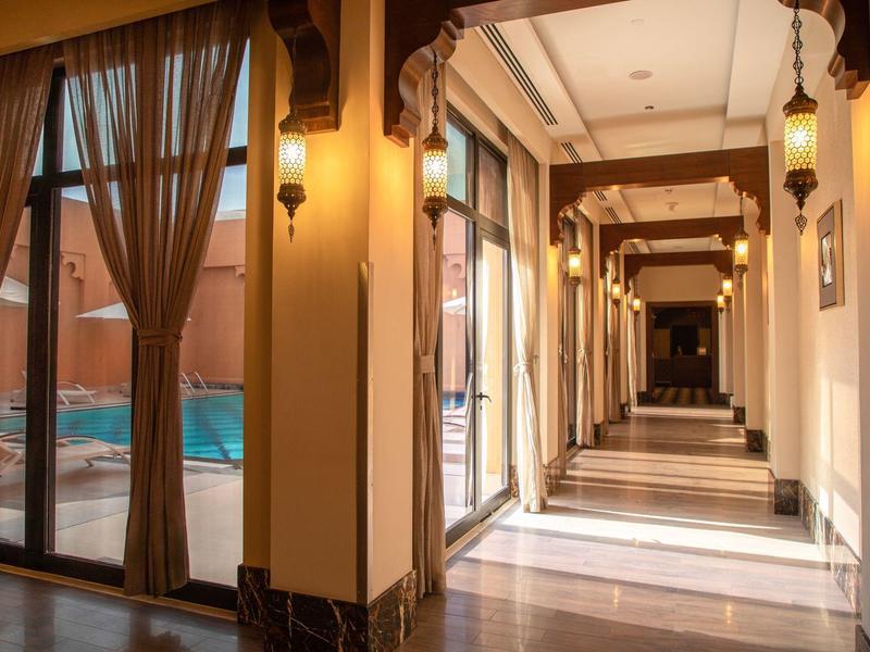 Heller Hotelflur mit großen Fenstern und Blick auf einen Pool im Freien.