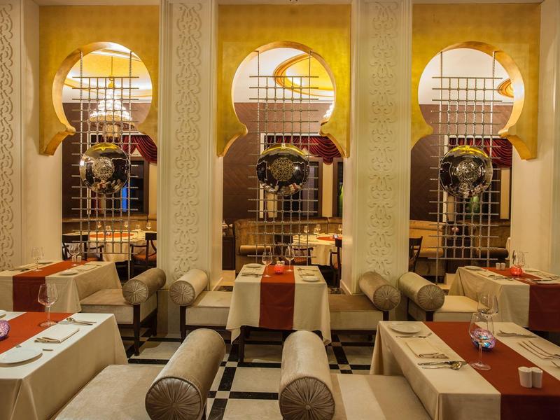 Elegantes Restaurant mit arabischen Bogenfenstern und gemütlichen Sitzbereichen in warmen Tönen.