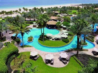 Tropische Hotelanlage mit Pools, Palmen, Liegestühlen und Blick auf den weißen Sandstrand.