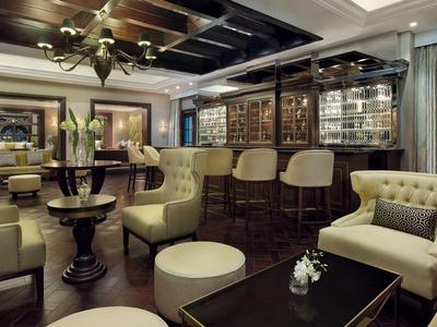 Elegante Bar mit Ledersesseln, Holztresen, Bücherregalen und gemütlicher Beleuchtung.