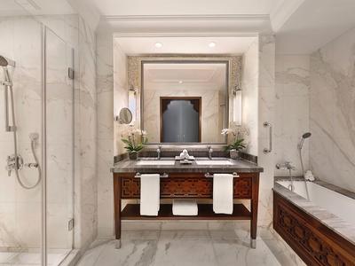 Elegantes Badezimmer mit Marmorwänden, Holzwaschtisch, großer Spiegel, Dusche und Badewanne.