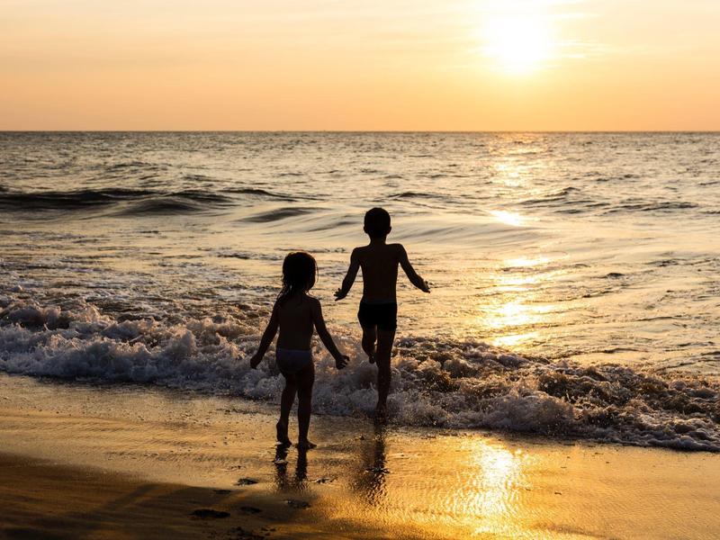 Habitación de hotel elegante con cama grande, área de estar, escritorio y grandes ventanas con cortinas.